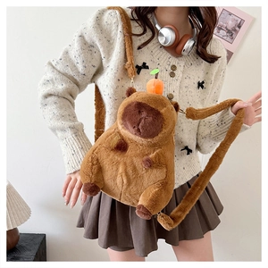 Brown plush capybara crossbody bag with orange fruit detail shown on a model