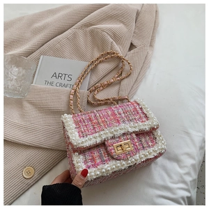 Close-up of pink tweed handbag featuring elegant pearl trim and golden metal twist lock