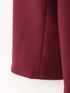 Close-up detail of burgundy wool fabric texture and high-quality stitching on the hem