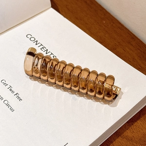 Vue détaillée de la spirale à cheveux en acrylique ambre avec détails dorés métalliques