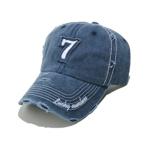 Detail of blue denim baseball cap with white number 7 patch and distressed hole accents