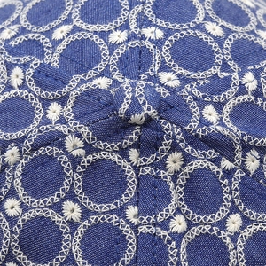 Macro di un cappellino in denim blu navy con dettagliati ricami floreali di colore bianco