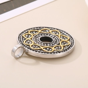 Macro view of a round silver pendant with pavé rhinestones and a gold infinity knot