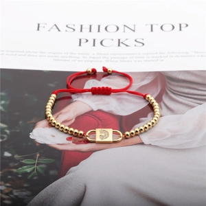 Detail of red string bracelet with gold beads and moon-shaped zircon lock charm