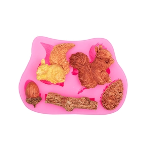 Detail of pink silicone mold with squirrel, acorn, and pinecone shapes for cake decorating