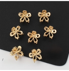 Set de ocho mini pinzas para el cabello doradas con forma de flor sobre cuero negro