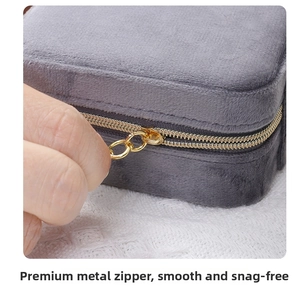 Detailed close-up of a smooth gold zipper on a grey velvet travel jewelry box