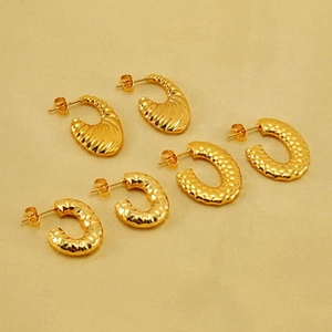 Détail des boucles d'oreilles C dorées à l'or 18 carats avec texture lave martelée