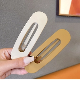 Macro detail of large matte hair clips in cream and ginger yellow with hollow design