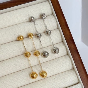 Detail of 18K gold and silver triple ball chain drop earrings on a jewelry tray