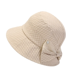 Detail of beige seersucker sun hat showing textured fabric, bow, and metal brand tag