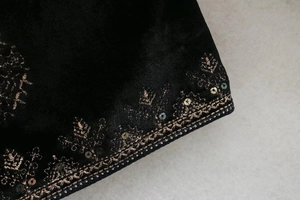 Gros plan de broderies dorées complexes et paillettes sur tissu en velours de soie noir