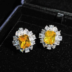 Macro shot of yellow gemstone earrings with halo diamonds in a black velvet box