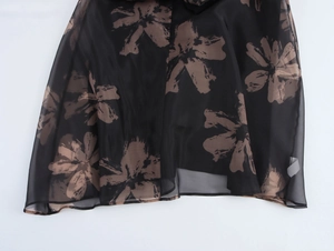 Détail de la robe en organza à fleurs avec tissu transparent et petits boutons noirs devant