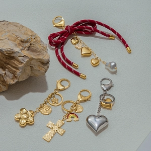 Detailed flat lay of stainless steel charms featuring baroque pearls and heart pendants
