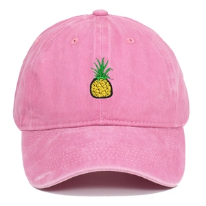 Close-up of bright yellow pineapple embroidery on washed pink cotton baseball cap