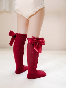 Detail of red cable-knit children socks featuring large bow decorations in palace style