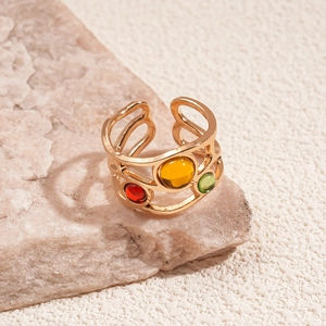 Macro detail of gold-plated open ring featuring red, yellow, and green gemstones