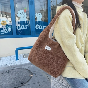 Detail of brown faux shearling tote bag with woven brand label and plush texture