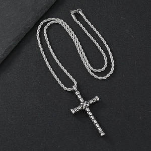 Vintage stainless steel cross pendant necklace with a twisted rope chain on stone background