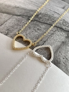 Close-up of gold and silver heart-shaped pendant necklaces with shiny cubic zirconia stones