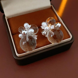 Detail of round crystal zircon and pearl stud earrings in a brown velvet jewelry box