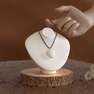 Detailed view of a white shell pendant necklace on a minimalist resin bust stand