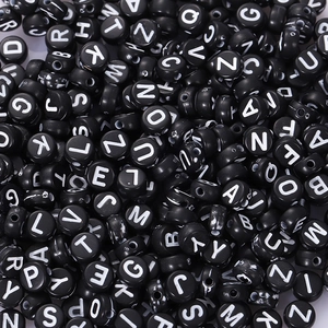 Macro view of black acrylic alphabet beads with white letters for DIY jewelry making