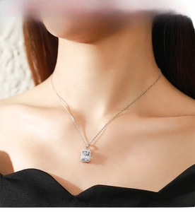 Detail shot of emerald cut zircon pendant necklace with halo setting on a female model