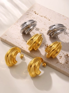 Detailed view of C-shaped wave textured metal earrings in gold and silver finish