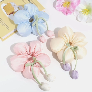 Detail of satin oversized floral scrunchies with green bows and tulip charms in three colors