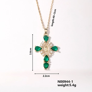 Detail view of gold cross pendant with green gemstone and dimension measurements