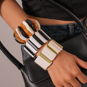 Macro detail of elastic resin bangles with acrylic resin and gold-tone metal blocks