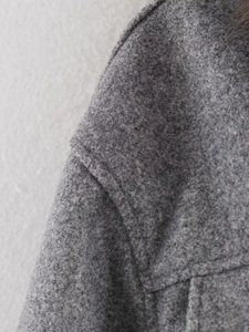 Close-up of gray wool jacket fabric showing plush texture and high-quality shoulder seams