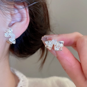 Close-up of elegant silver bow stud earrings with zircon inlay worn by a model