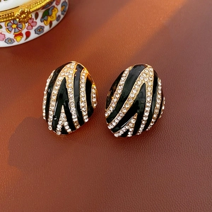 Macro shot of vintage enamel zebra stripe earrings with crystals on leather