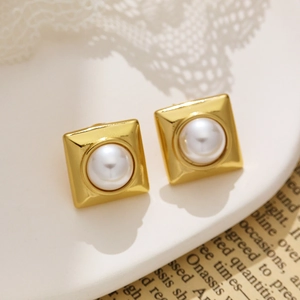 Macro shot of square gold vintage earrings with iridescent white pearls on lace