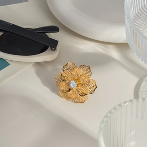 Detailed view of hollow camellia ring in 18K gold finish with a sparkling zircon center