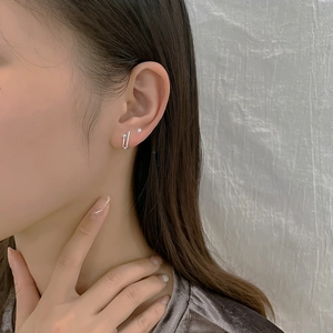 Close-up of a silver paperclip earring on model's ear with a minimalist U-shaped design