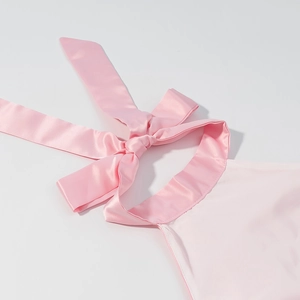Close-up of pink satin halter top with a large bow-tie back detail and silky texture