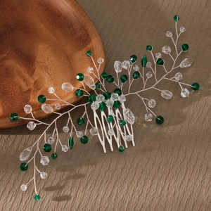 Detail of silver hair comb with emerald green crystal beads on a rustic wood surface