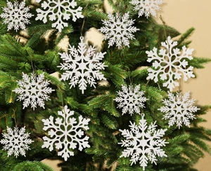 Close-up of white glitter snowflake ornaments hanging on Christmas tree branches