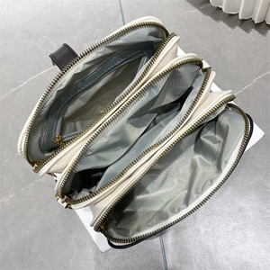 Top view of cream white shoulder bag with three main zippered compartments and grey lining