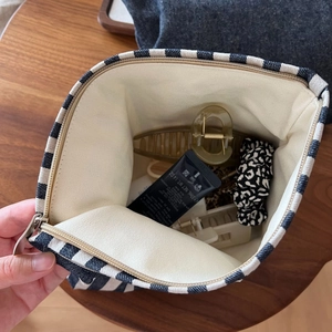 Macro detail of the spacious striped canvas pouch interior holding various beauty items