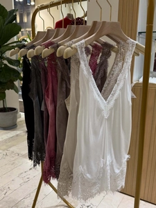Close-up of delicate lace trim on a white silk camisole top with elegant V-neck detail