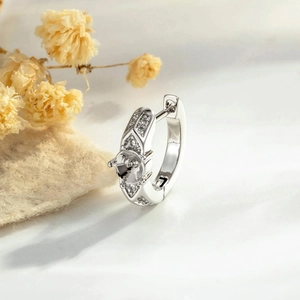 Silver quilted pavé zircon hoop earring with center mount on a soft floral background