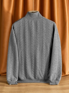 Dettaglio della trama a trecce su un maglione grigio a collo alto con motivi jacquard