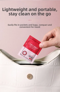 Portable stain removal wipe for clothing being placed into a stylish white leather bag