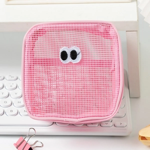 Close-up of pink mesh makeup bag with cute embroidered eyes on a desktop background