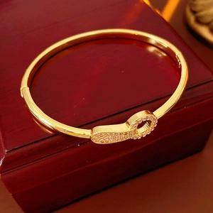 Close-up of gold plated zircon bangle with oval spring clasp on a luxury jewelry box
